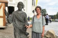 Künstlerin steht neben einer Christus-Skulptur