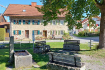 Haus mit Tuffstein, im Vordergrund ein Brunnen.