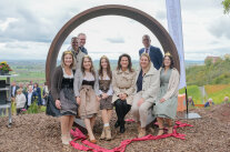 Staatsministerin Kanier mit den fränkischen Weinköniginnen sitzt auf einer ovalen Stahlkonstruktion, durch die der Panoramablick geht.